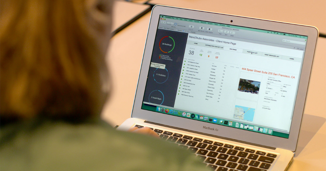 Photo of a laptop screen, over the shoulder of a woman with shorter red hair. The photo is for an article about 50 ways to use FileMaker.